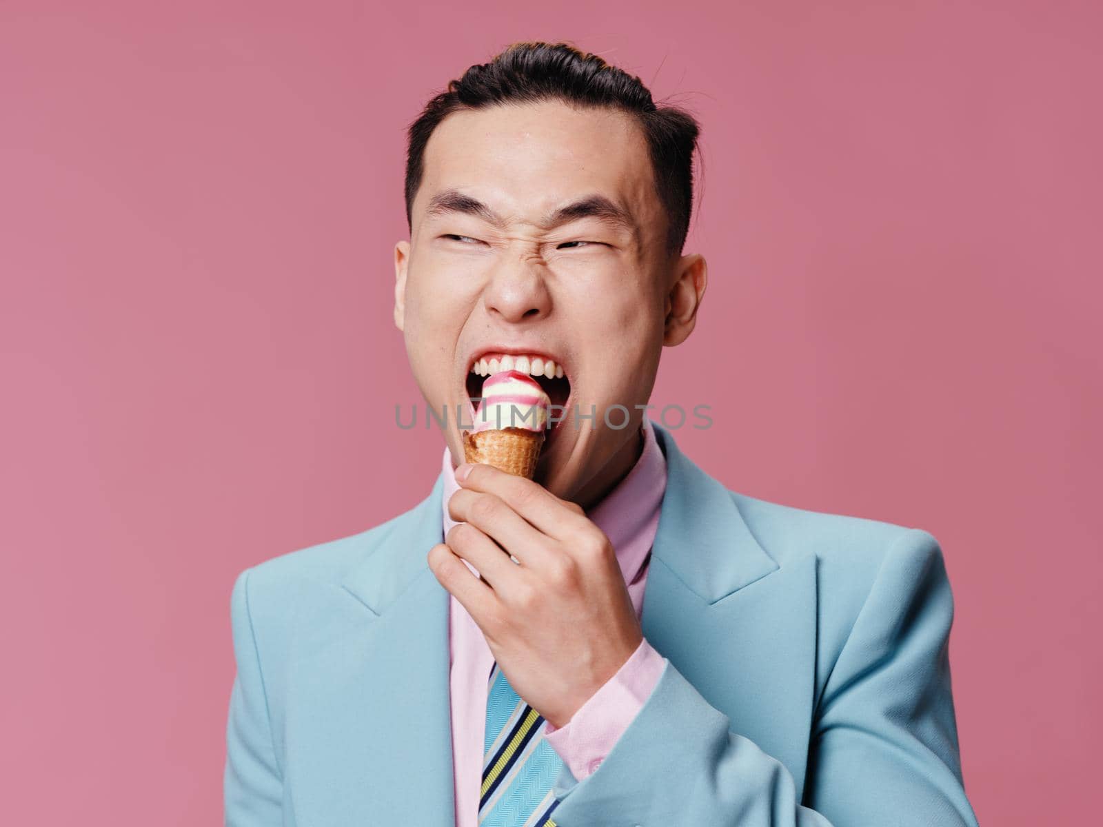 Cute man eating ice cream blue jacket lifestyle pink background. High quality photo