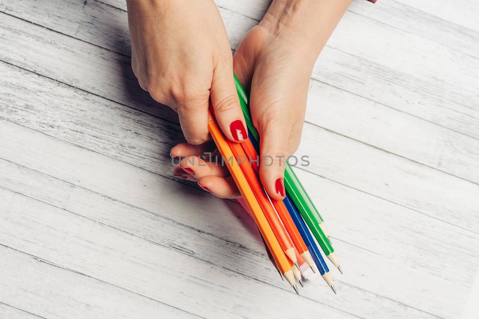 colored pencils female hands top view wooden table office. High quality photo