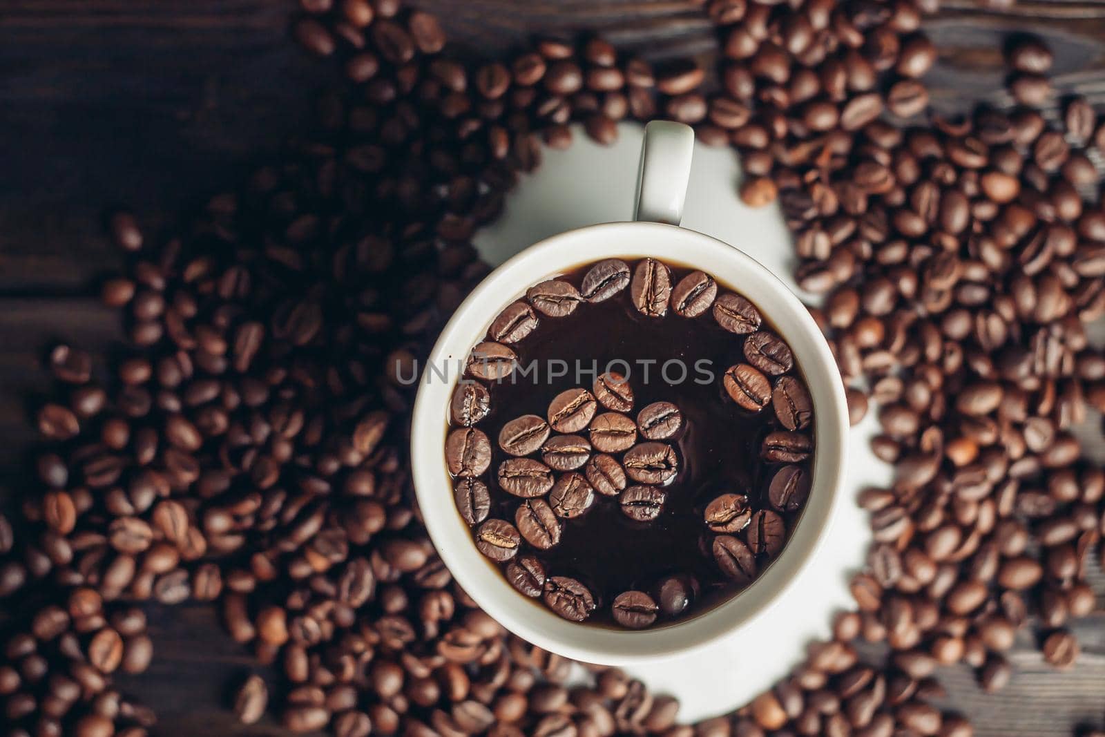 aromatic drink in a cup and coffee beans scattered on a wooden background. High quality photo