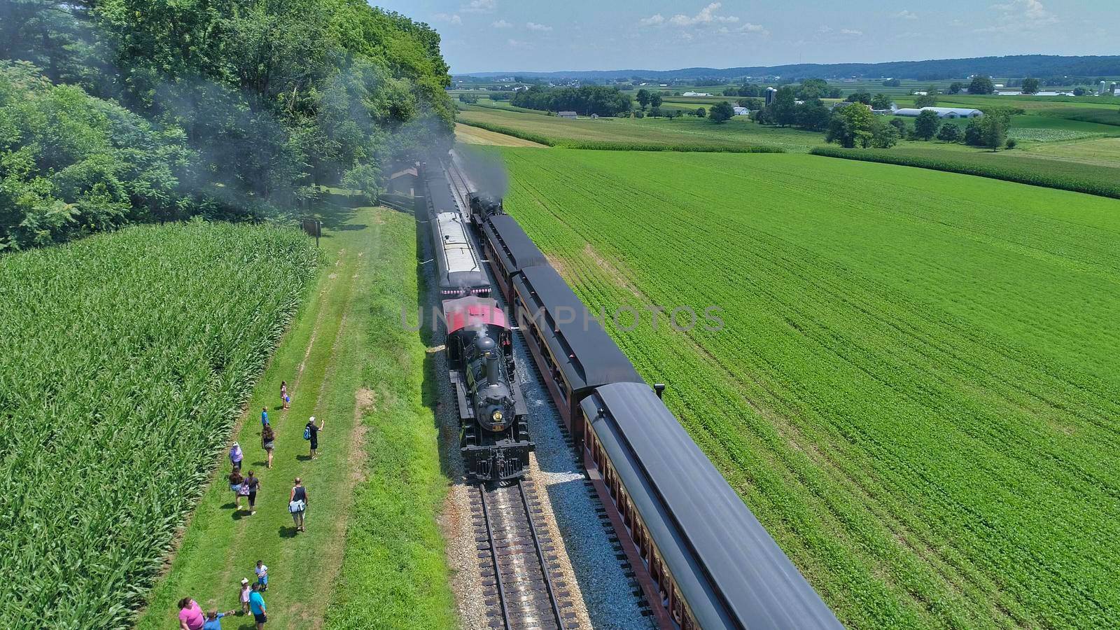 Aerial View of An Antique Restored Steam Locomotive Blowing Smoke and Steam Traveling Thru Farmlands and Countryside on a Sunny Summer Day