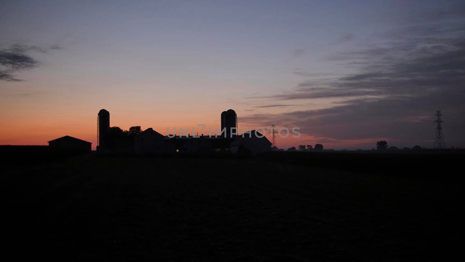 View of a Sunrise Looking over an Amish Farm with Farm House Barn and Silos
