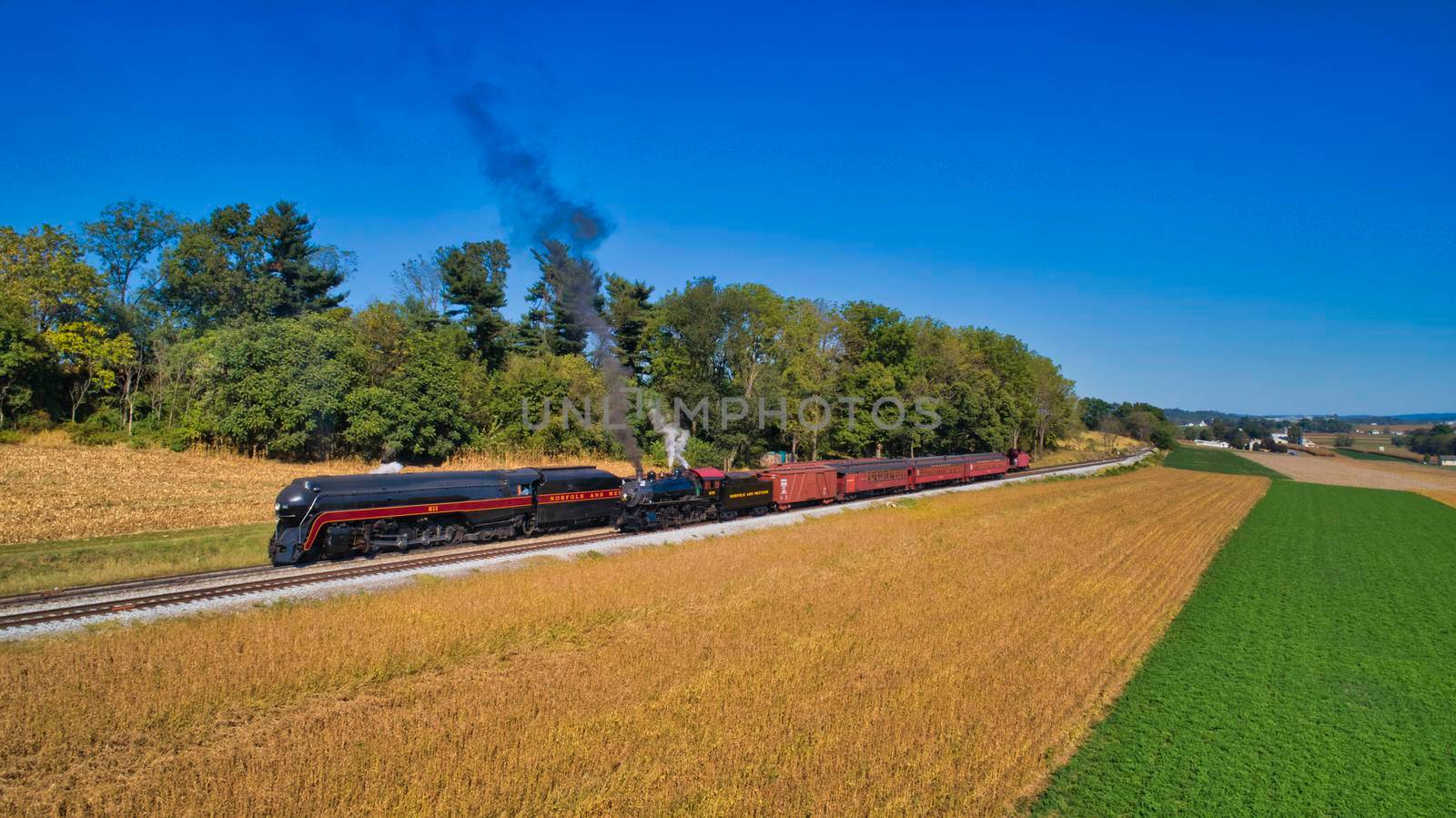 Aerial View of An Antique Restored Steam Locomotive Blowing Smoke and Steam Traveling Thru Farmlands and Countryside on a Sunny Summer Day