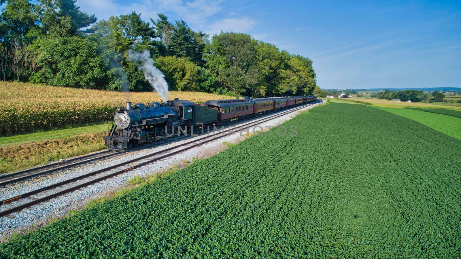Aerial View of An Antique Restored Steam Locomotive Blowing Smoke and Steam Traveling Thru Farmlands and Countryside on a Sunny Summer Day