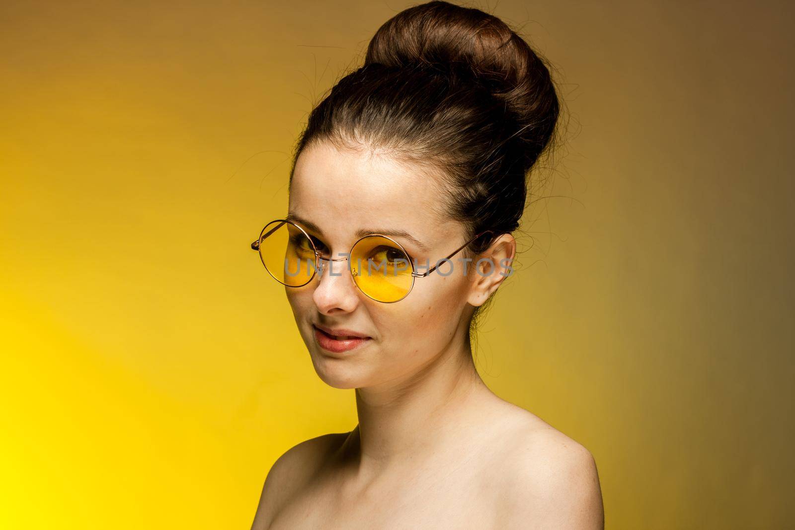 woman in yellow glasses naked shoulders gestures with hands. High quality photo