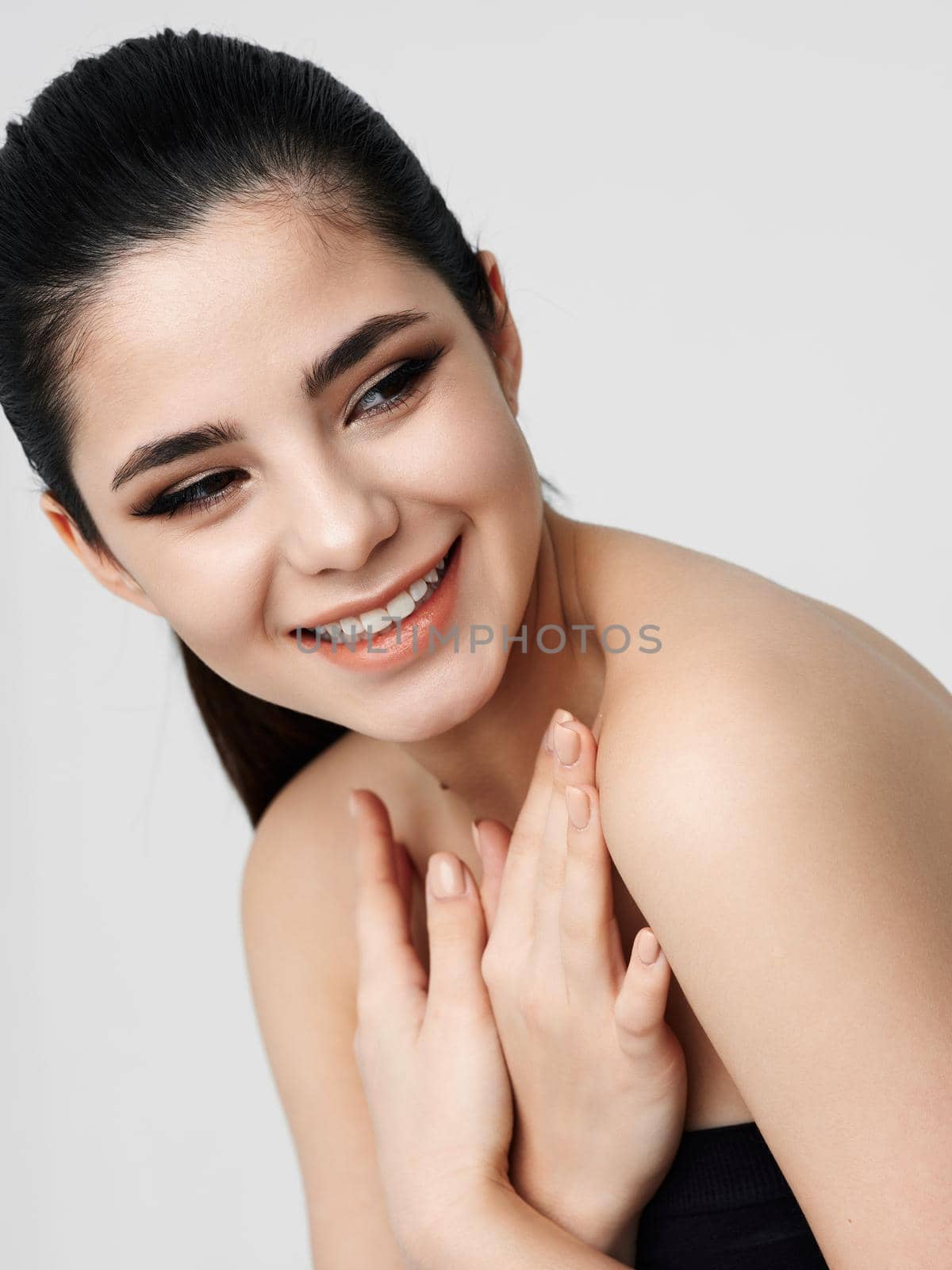 woman with bare shoulders holds hand near face makeup charm. High quality photo