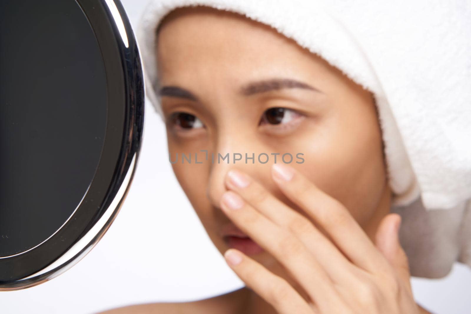 woman of asian appearance touches her face with her hand and looks in the mirror clean skin. High quality photo