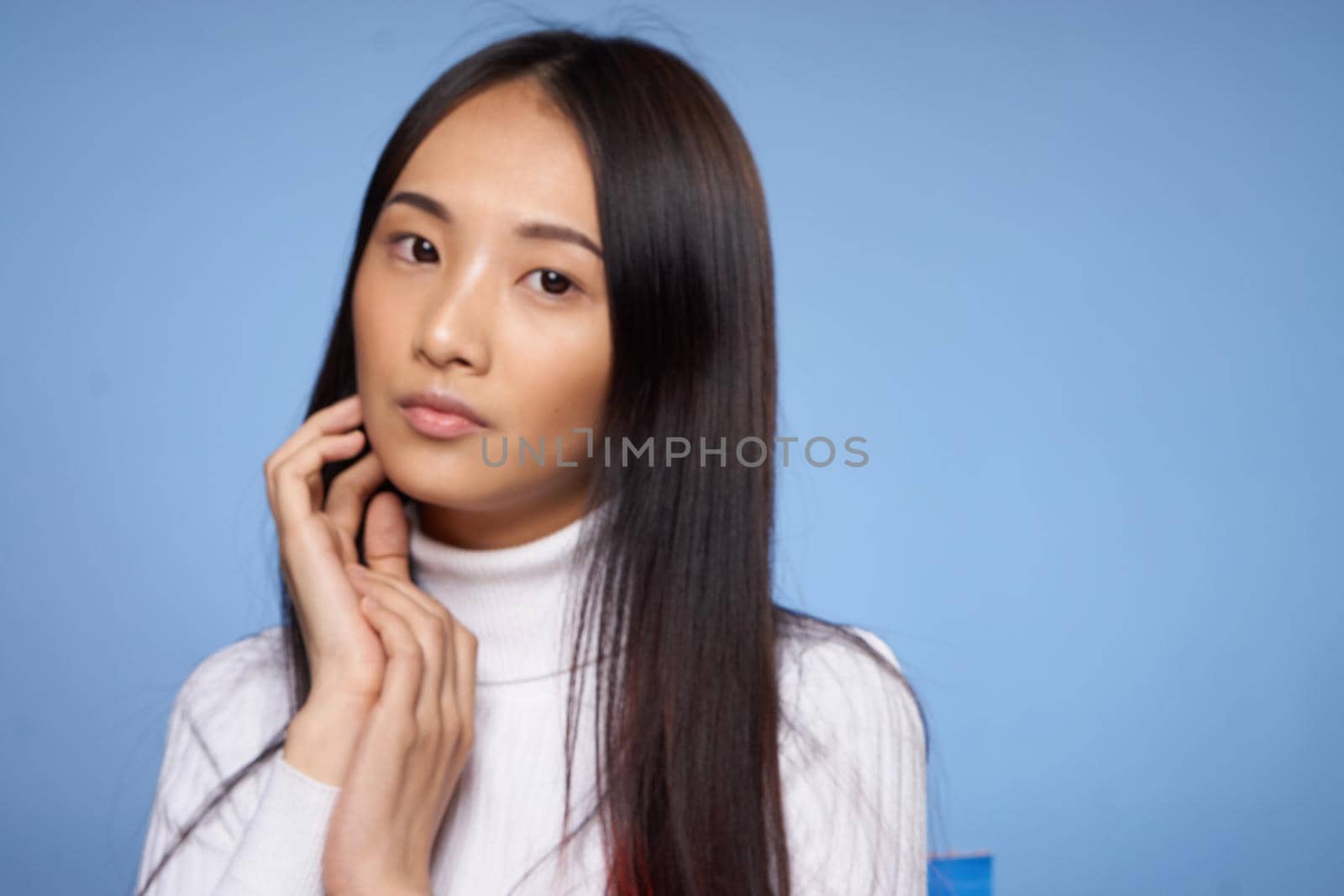 pretty woman with dark hair in white sweater gestures with her hands clean skin cosmetology. High quality photo