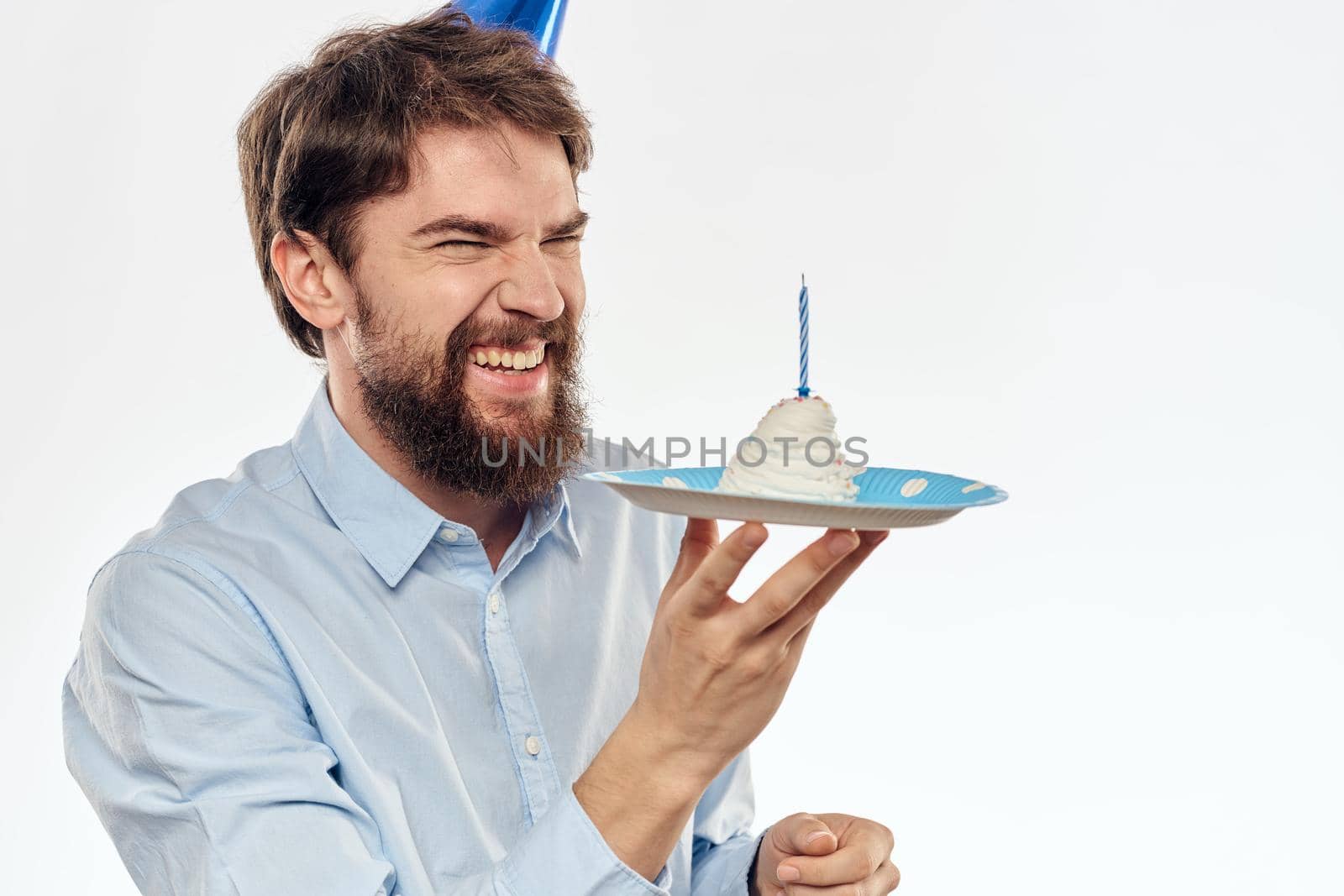 A man with a cake plate and in a blue shirt on a light background birthday party corporate cap. High quality photo
