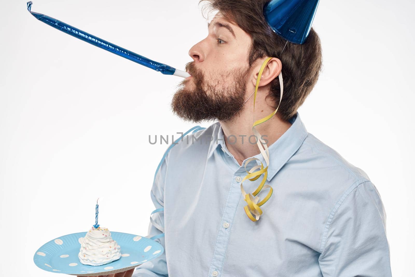 A man with a cake plate and in a blue shirt on a light background birthday party corporate cap. High quality photo
