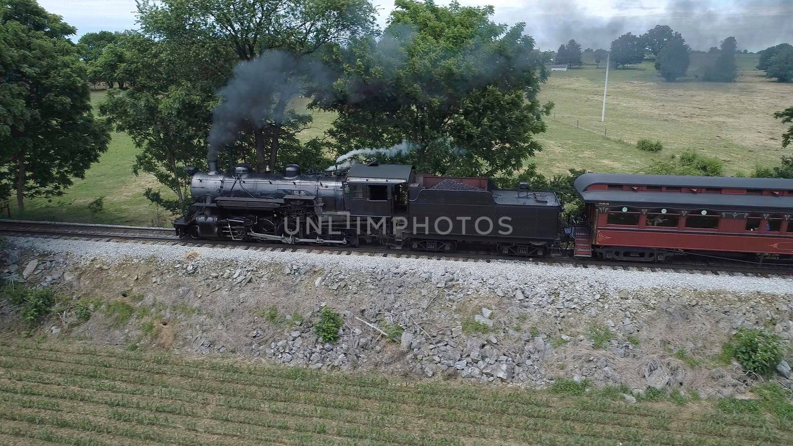 Aerial View of An Antique Restored Steam Locomotive Blowing Smoke and Steam Traveling Thru Farmlands and Countryside on a Sunny Summer Day