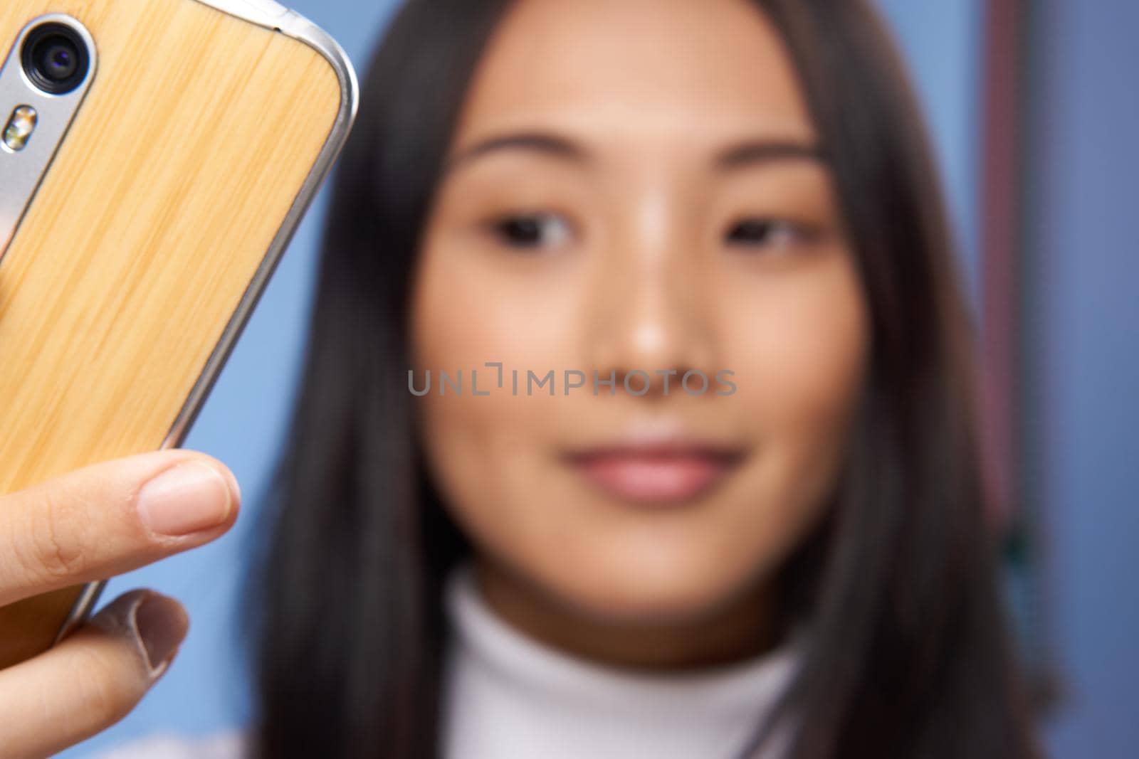 woman asian appearance attractive look phone close up studio blue background. High quality photo