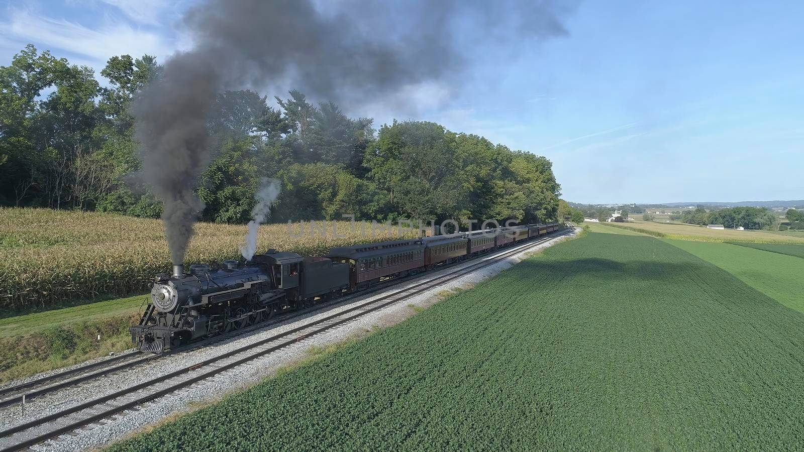 Aerial View of An Antique Restored Steam Locomotive Blowing Smoke and Steam Traveling Thru Farmlands and Countryside on a Sunny Summer Day