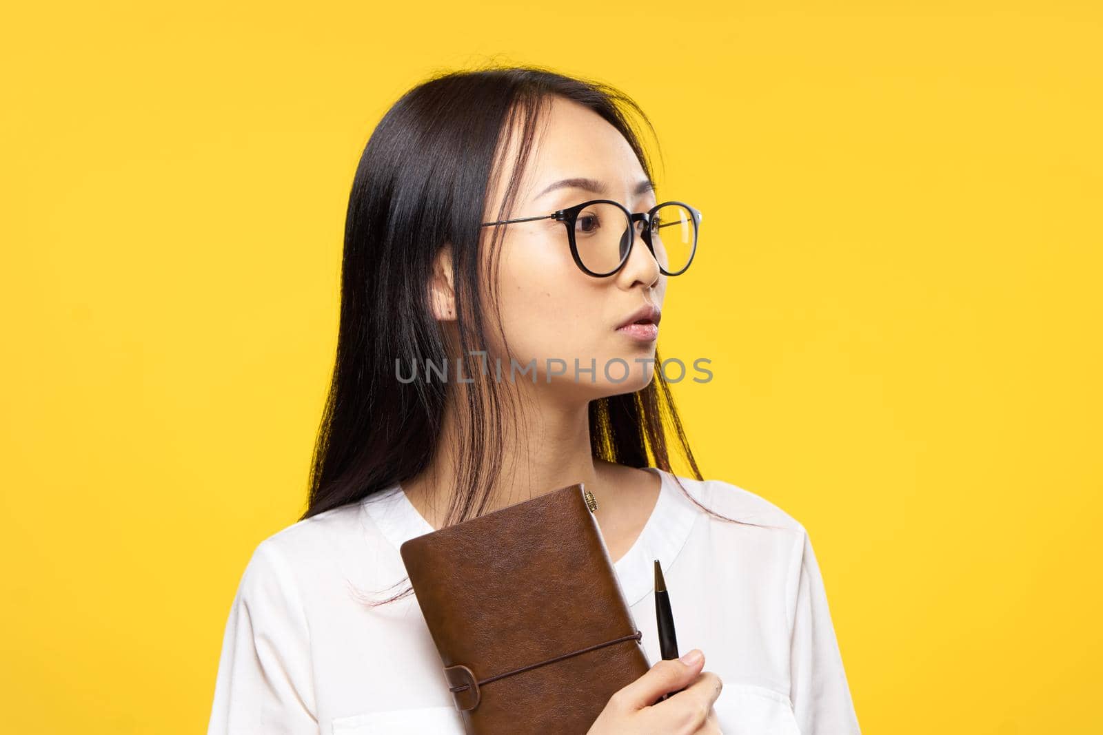 Business woman in glasses holding notepad in hands official yellow isolated background. High quality photo