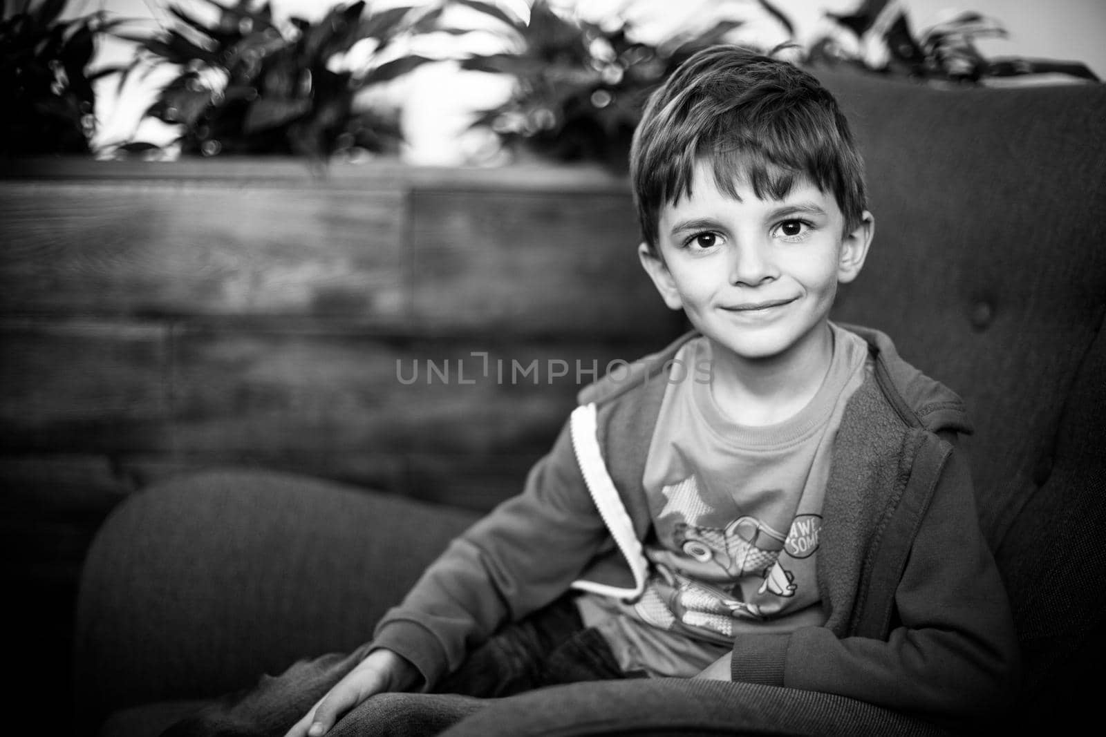 smiling young boy sitting on the sofa looking at camera, black and white shot