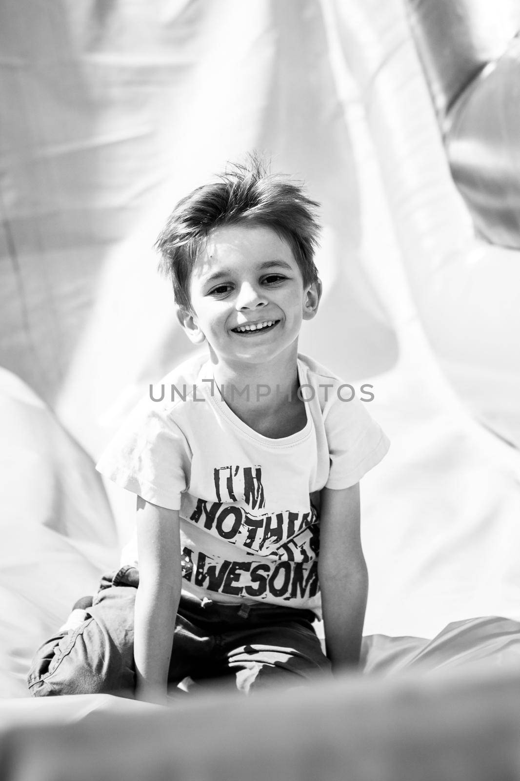 Smiling little boy playing on inflatable slide, looking at camera by zhu_zhu