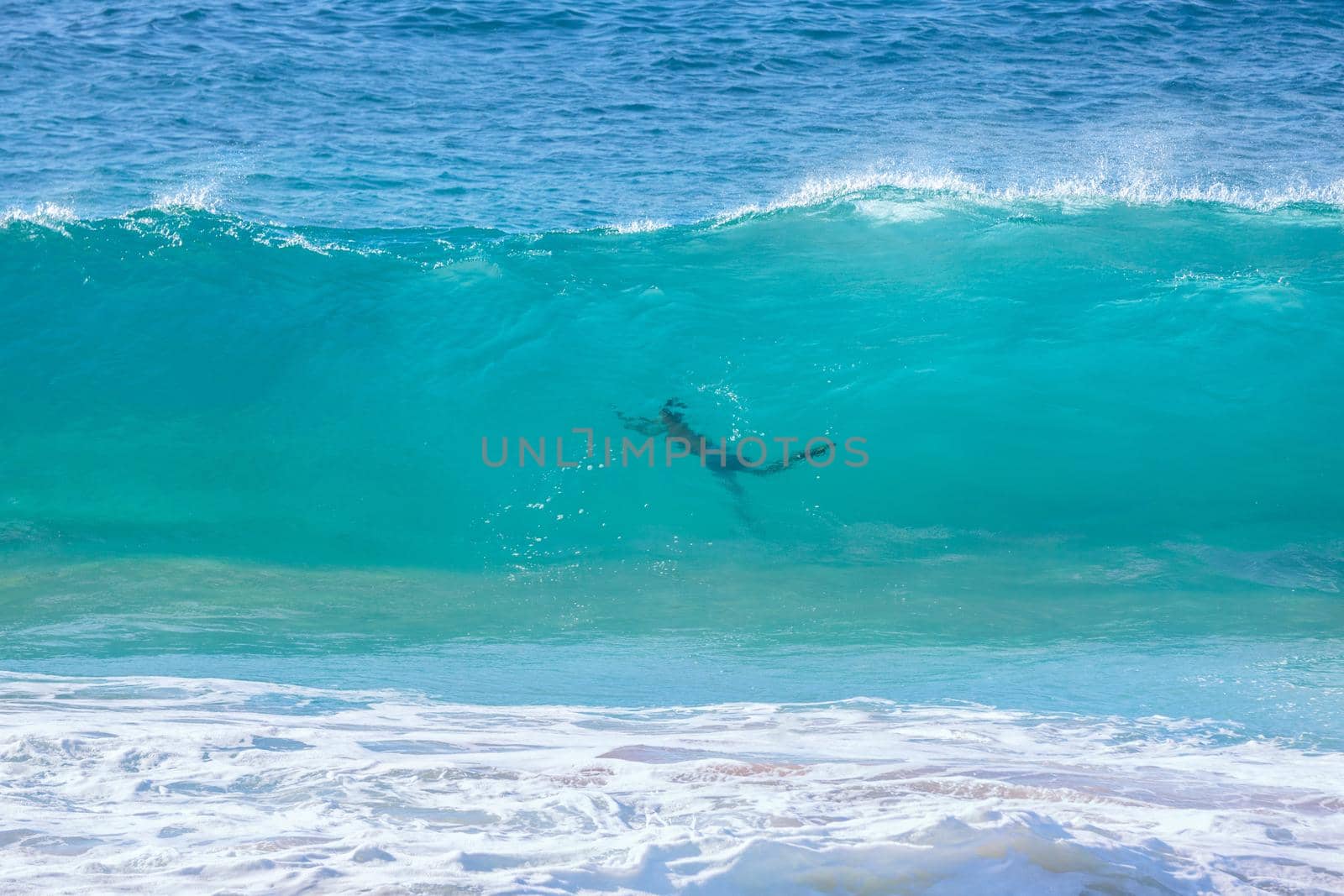 turquoise wave with people silhouette at Sandy Beach, Oahu, Hawaii USA