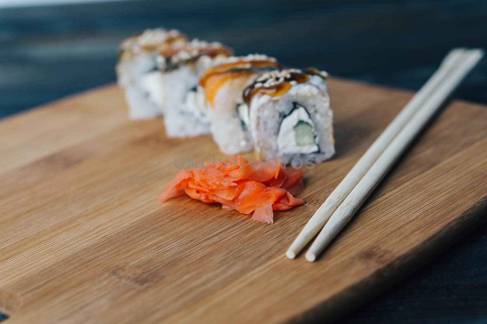 sushi rolls red ginger chopsticks wood board close-up. High quality photo