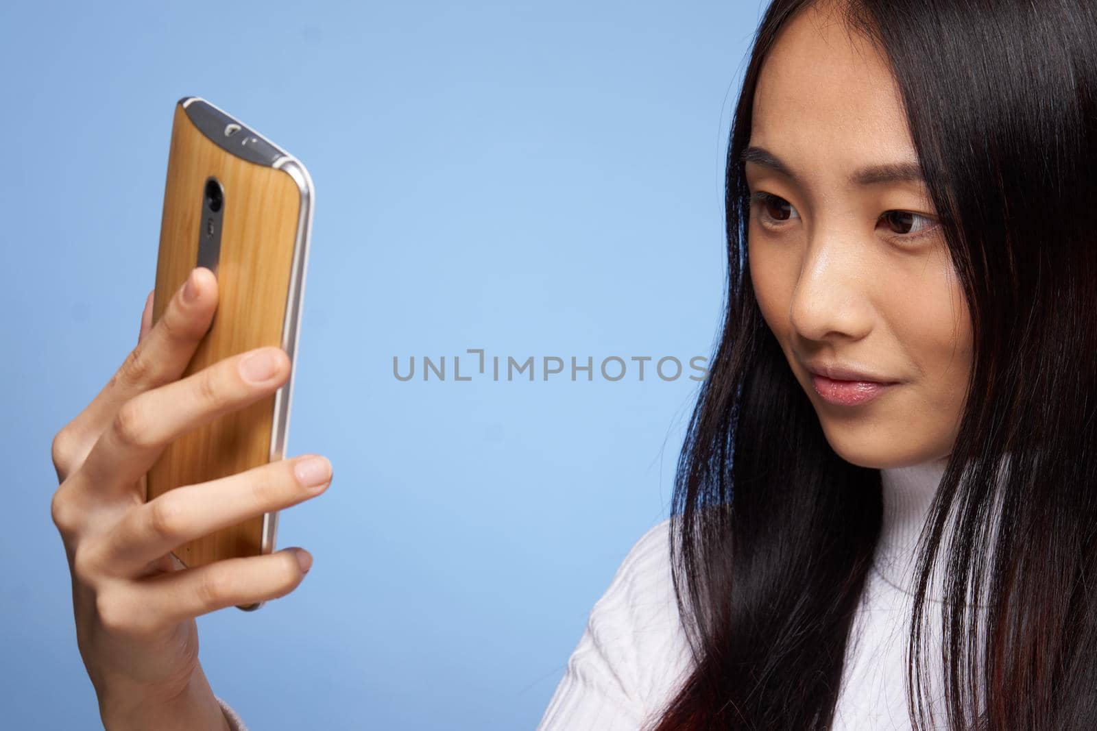 woman asian appearance phone in hand communicating internet blue background. High quality photo