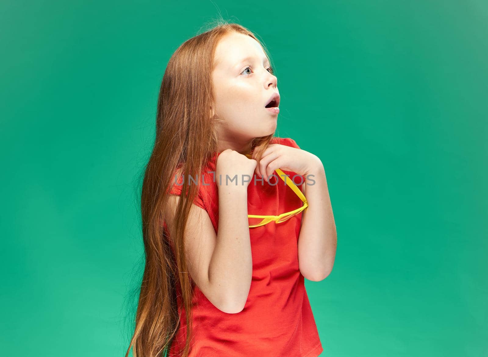 cute red-haired girl with glasses on her head red t-shirt Studio Green background. High quality photo