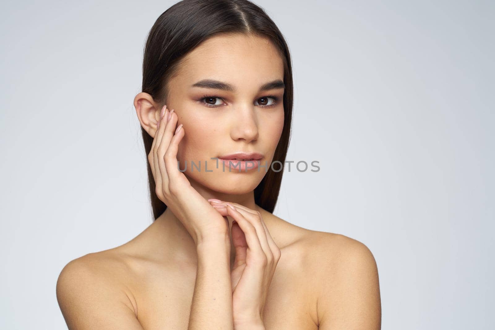 Woman with long hair bared shoulders clean skin body care light background. High quality photo
