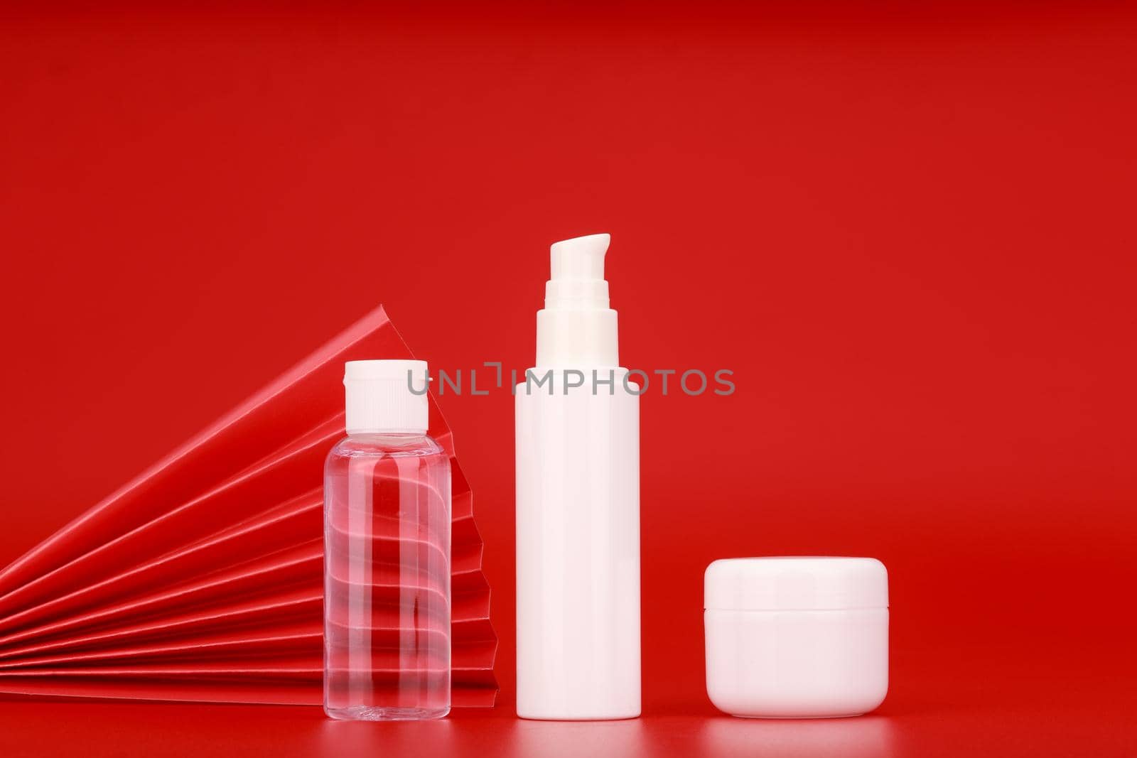 Set of skin care products, lotion, cream and scrub against red background decorated with waver. Concept of luxury or asian style beauty products
