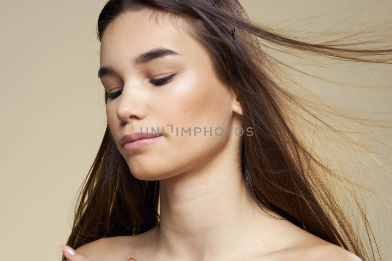 Pretty woman naked shoulders long hair body care beige background. High quality photo