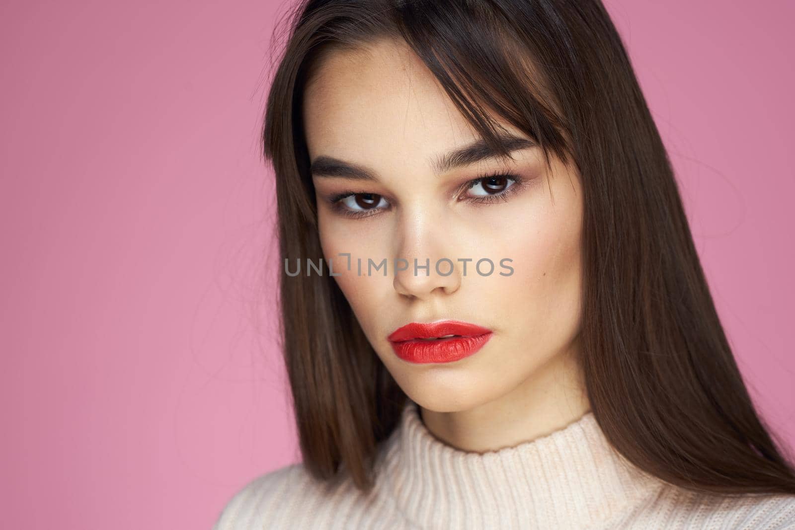 Beautiful brunette red lips white blouse close-up attractive view pink background. High quality photo