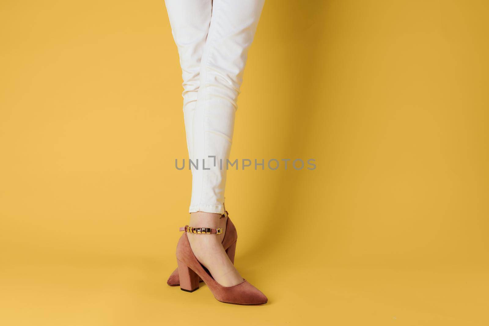 female feet in shoes fashionable clothes attractive look yellow background. High quality photo