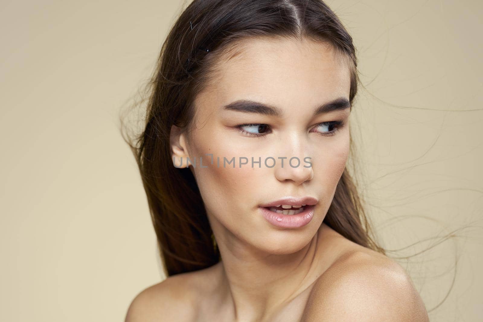 Pretty woman naked shoulders cosmetics clean skin hair care beige background. High quality photo