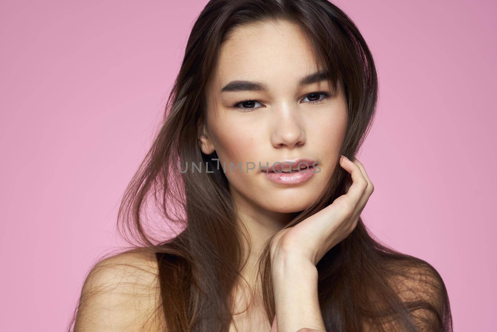 Pretty brunette naked shoulders clear skin pink background. High quality photo