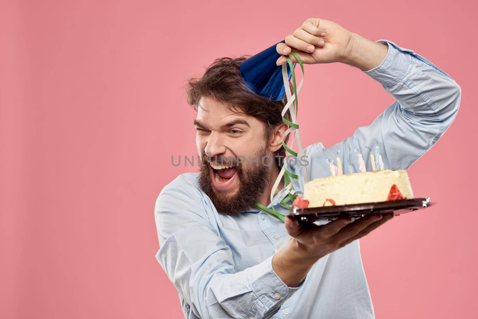 Bearded man with cake on pink background birthday party corporate emotions model loneliness. High quality photo