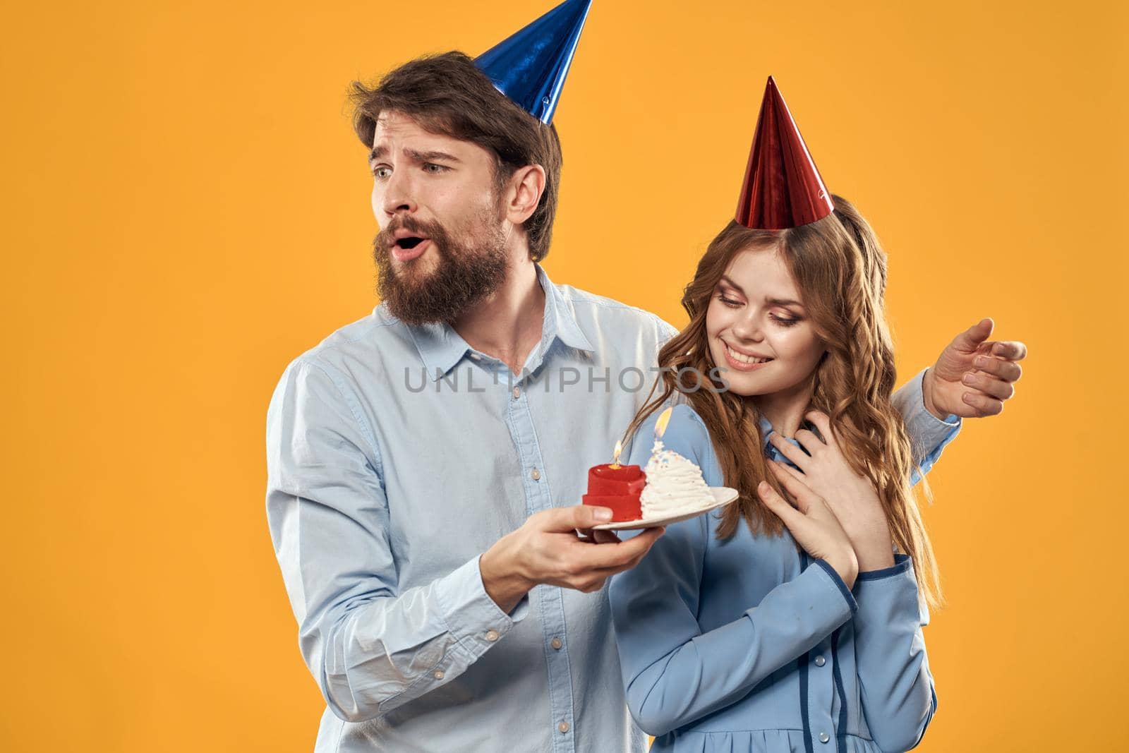 Birthday party man and woman in a cap with a cake on a yellow background cropped view. High quality photo