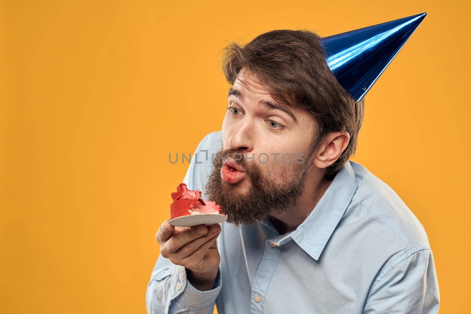 Man with cake on yellow background birthday party hat cropped view. High quality photo