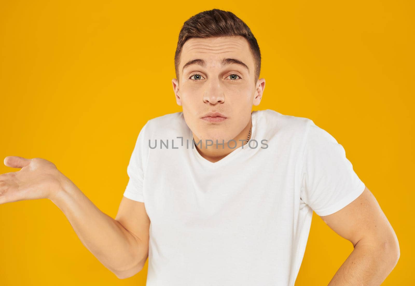 Angry guy gesturing with his hands on a yellow background cropped view. High quality photo