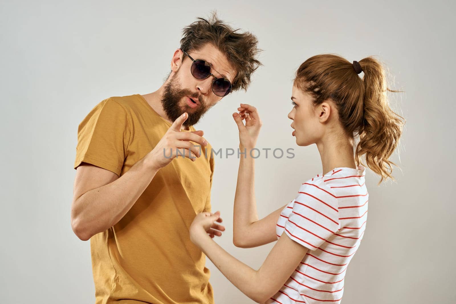 man in sunglasses next to woman in striped t-shirt emotions communication fashion studio fun. High quality photo