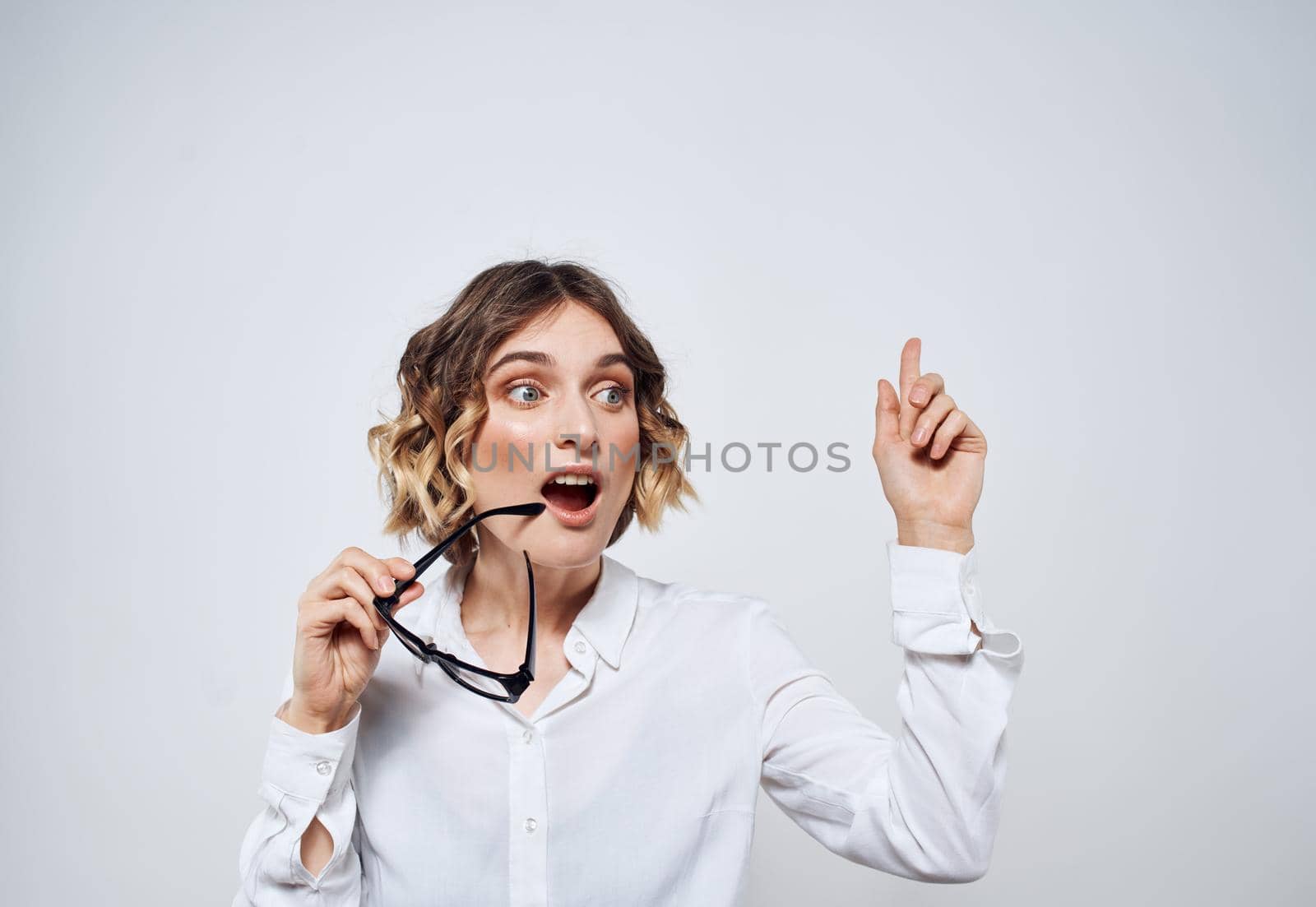 Emotional woman in a white shirt with glasses in her hands on a light background Copy Space. High quality photo