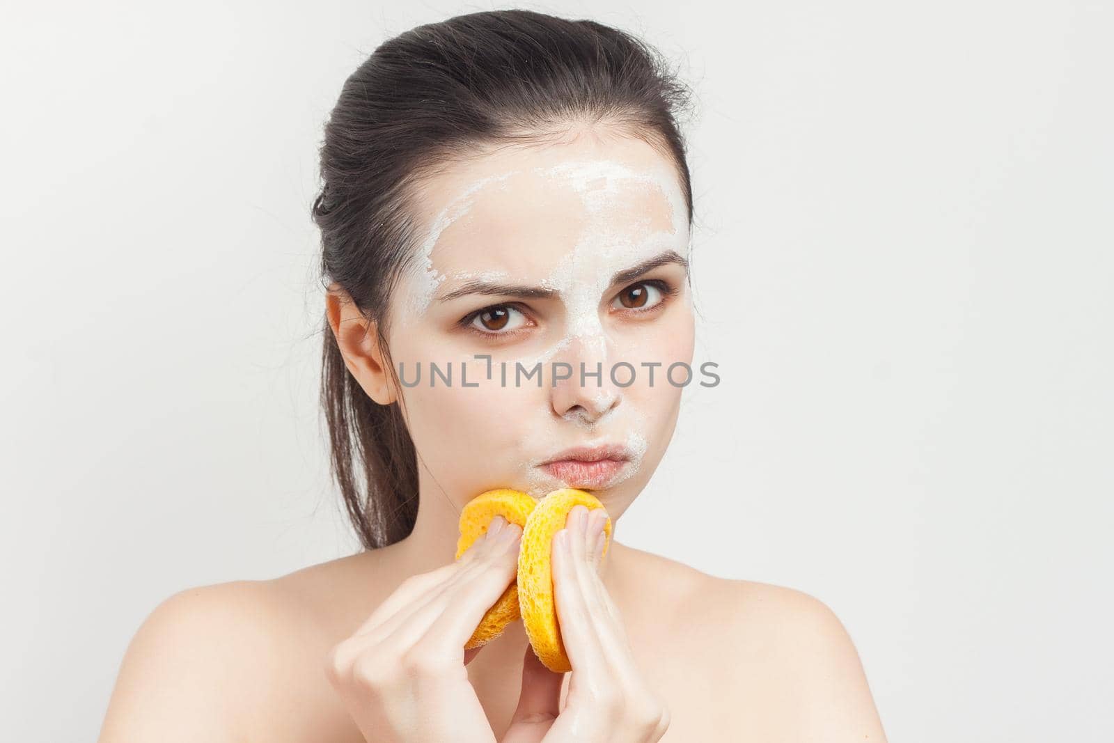 woman with sponges in hands cream mask on face cropped view. High quality photo
