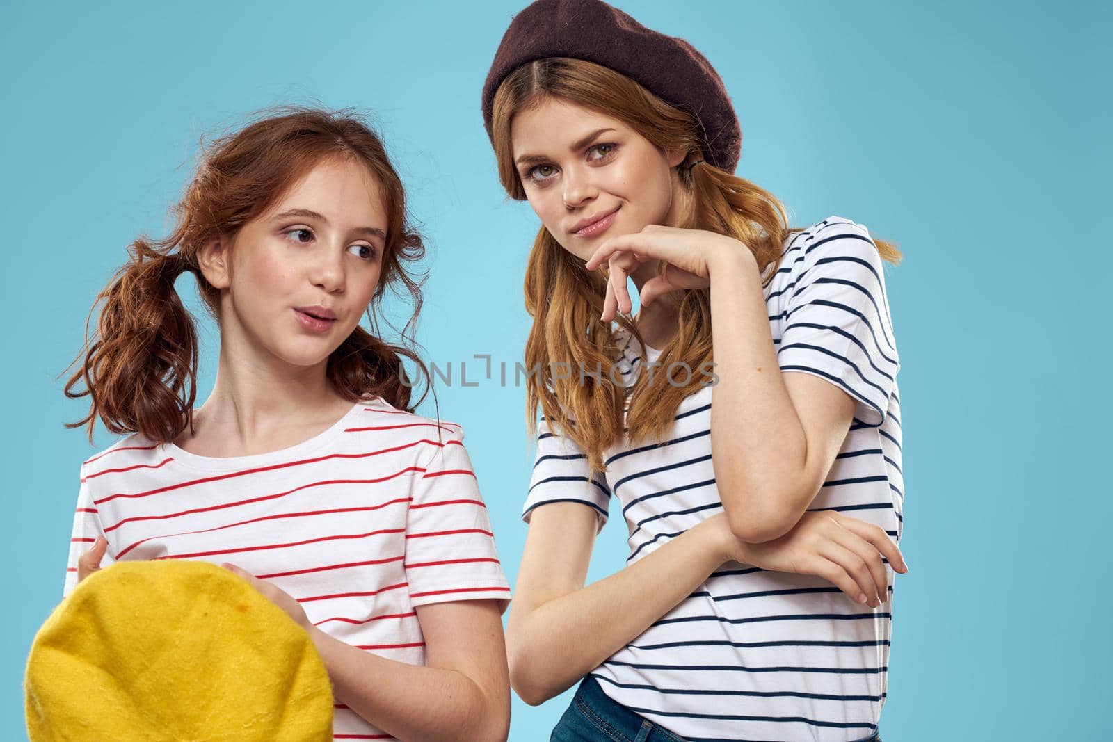 Mom and daughter striped T-shirts hugs fun lifestyle blue background. High quality photo