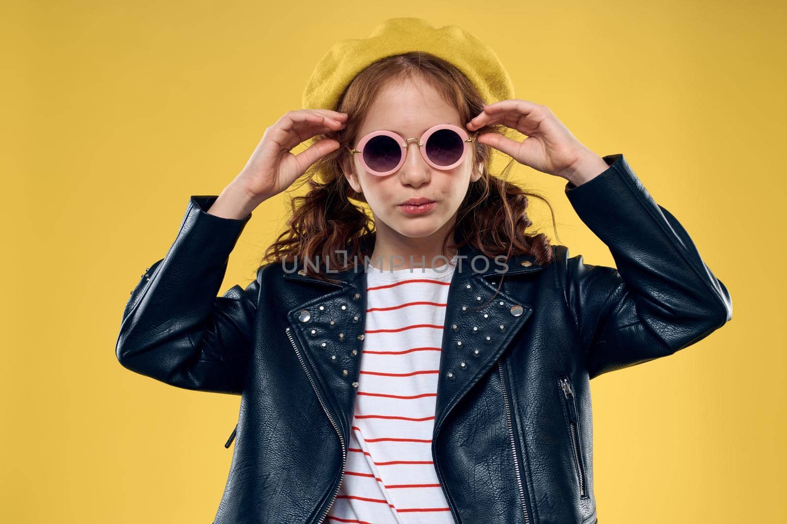 Cheerful little girl in sunglasses and hat lifestyle studio yellow background fashion. High quality photo
