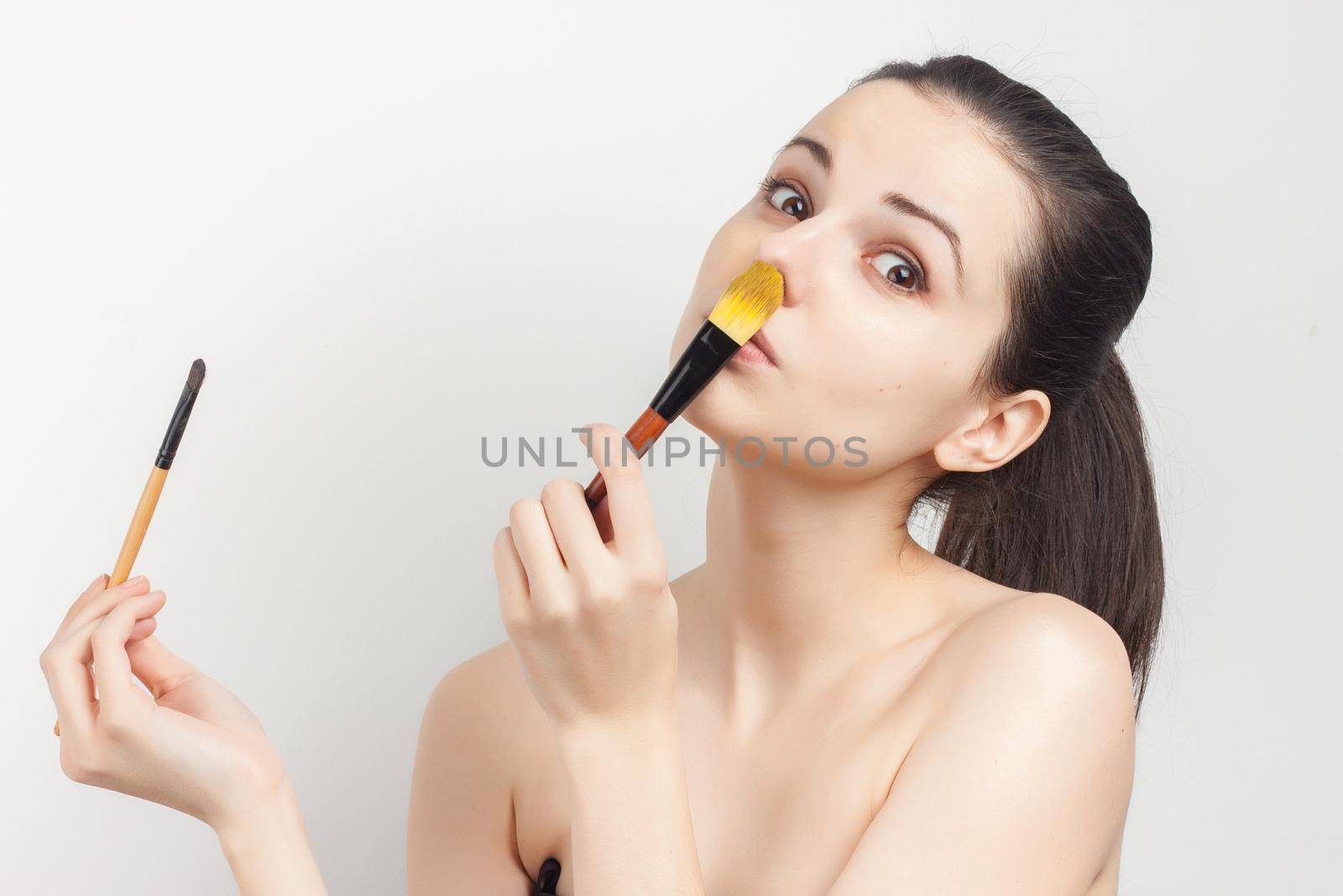 cheerful woman naked shoulders brushing cream on face. High quality photo