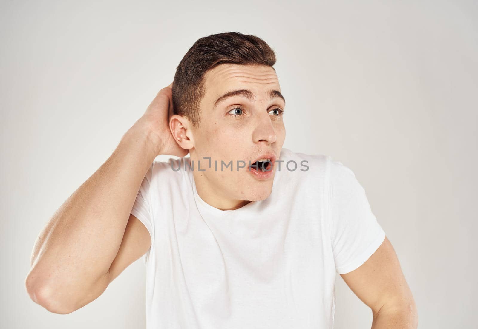 Nice guy in a white T-shirt on a light background cropped view portrait close-up. High quality photo