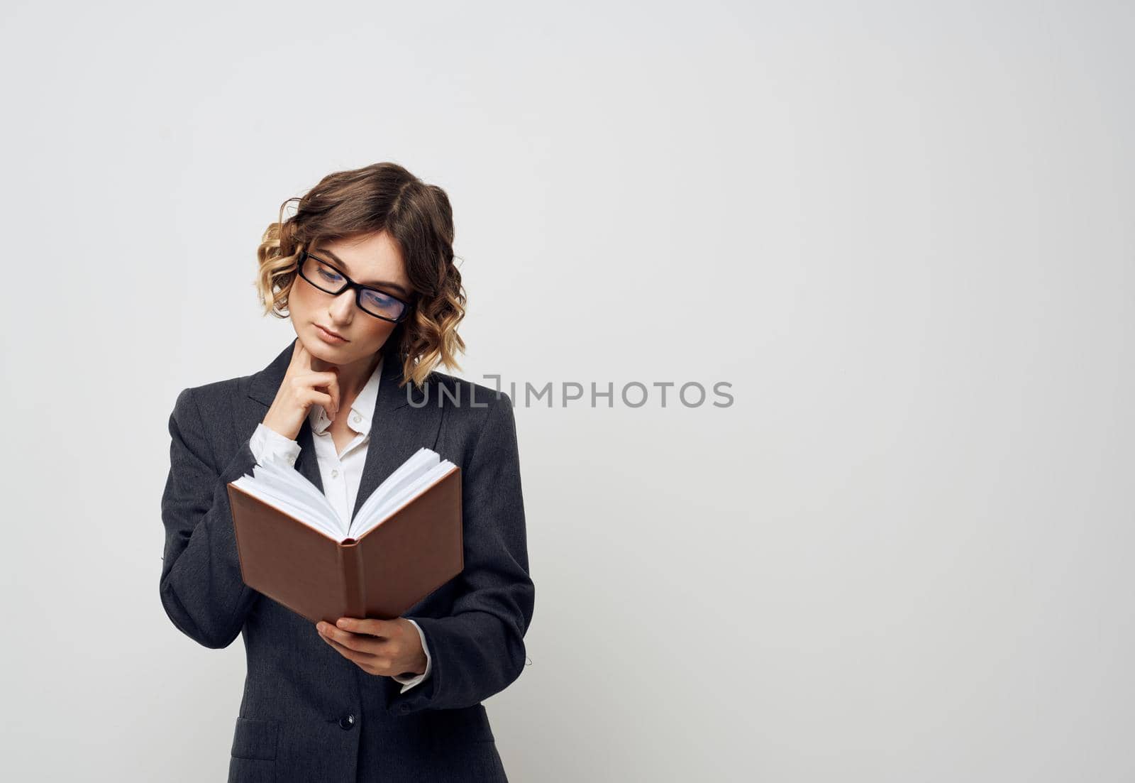 Business woman with a book in her hands on a light background Puzzled look Copy Space by SHOTPRIME