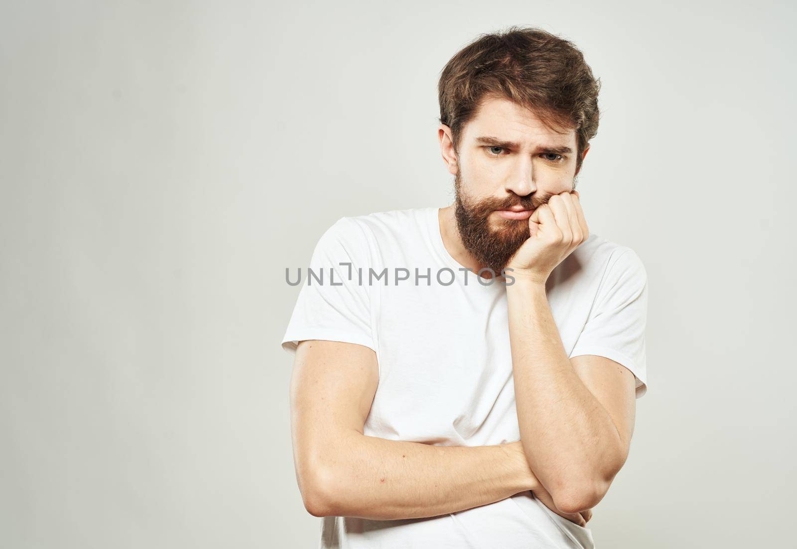 Man touches face with hands emotions model light background. High quality photo