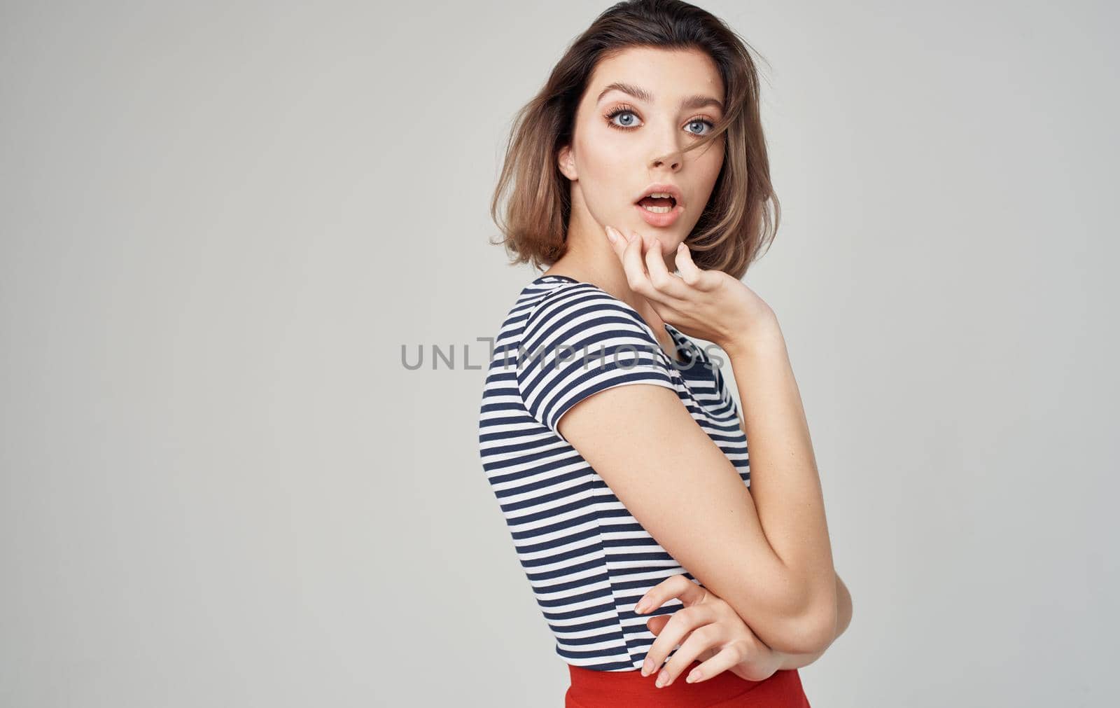 pretty model woman in striped t-shirt gesturing with hands on gray background Copy Space. High quality photo