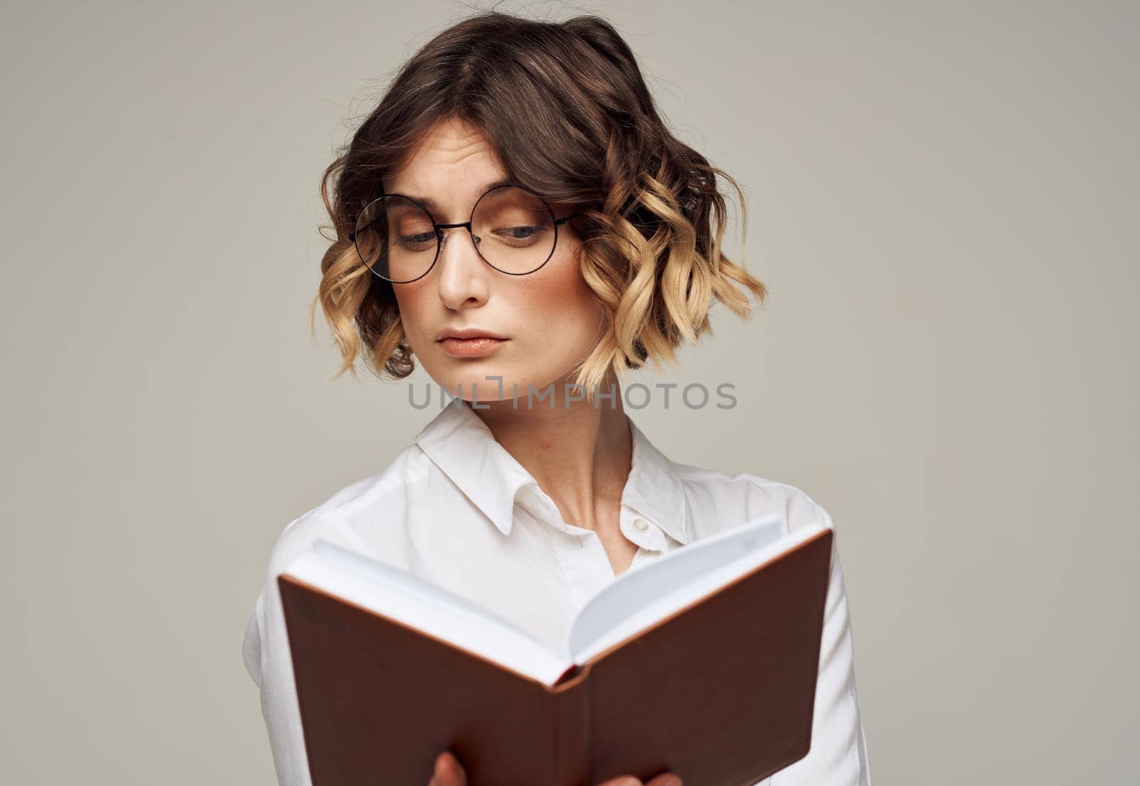 Literate woman with book in hands and in glasses white shirt education model by SHOTPRIME