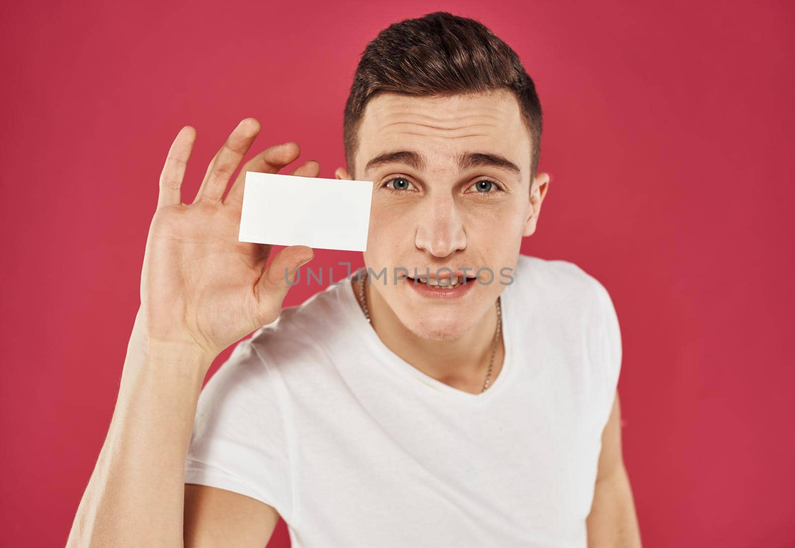 A man with a business card on a red background gestures with his hands cropped view by SHOTPRIME