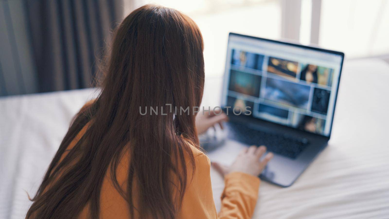 woman lying in bed in front of laptop working at home internet by SHOTPRIME