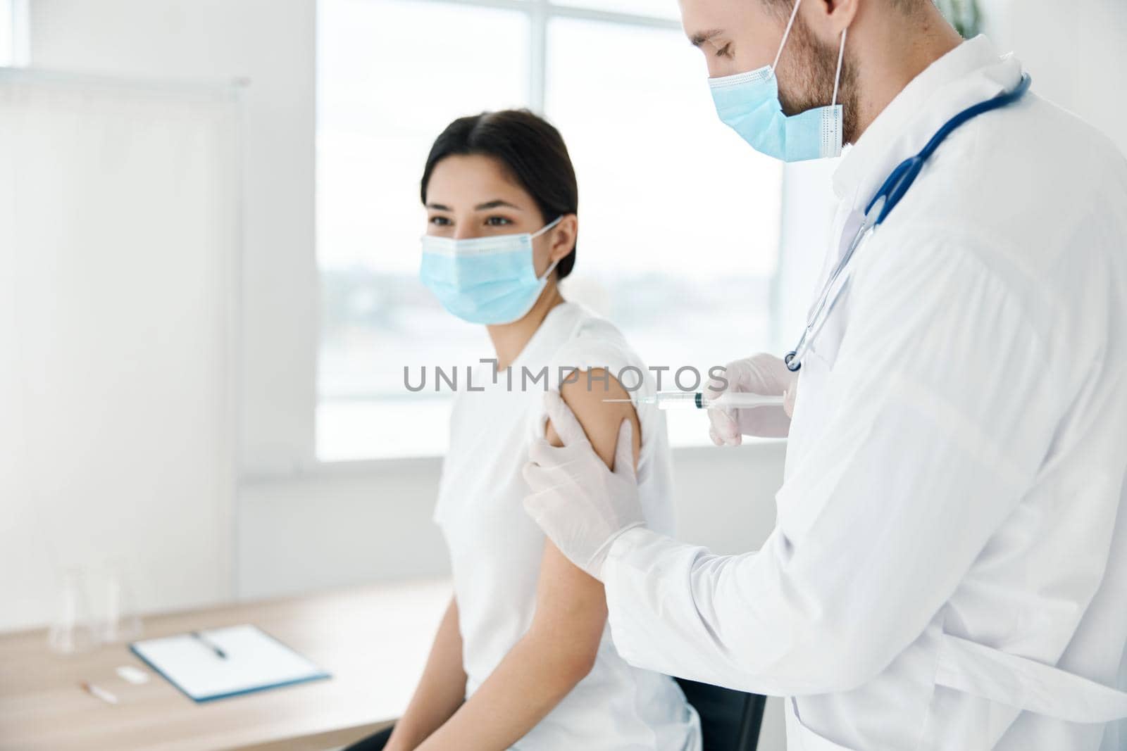 woman in medical mask doing coronavirus vaccine and doctor with syringe . High quality photo