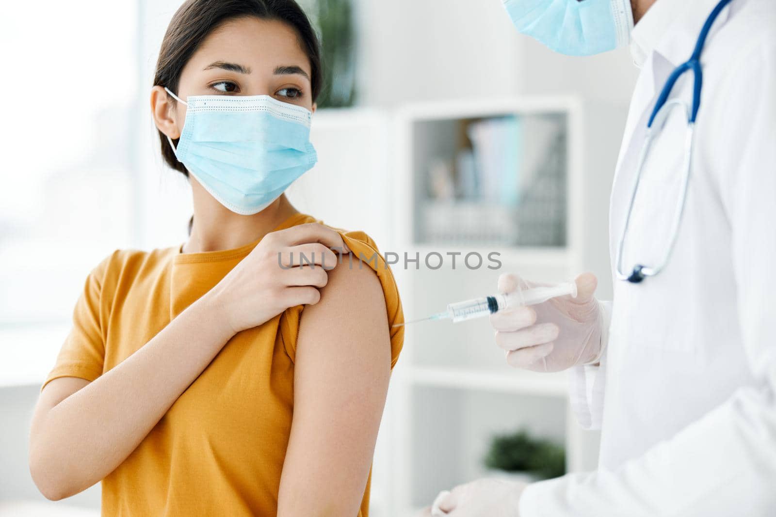 a patient in a hospital and a doctor in protective gloves inject a vaccine into the shoulder of a woman in a t-shirt. High quality photo