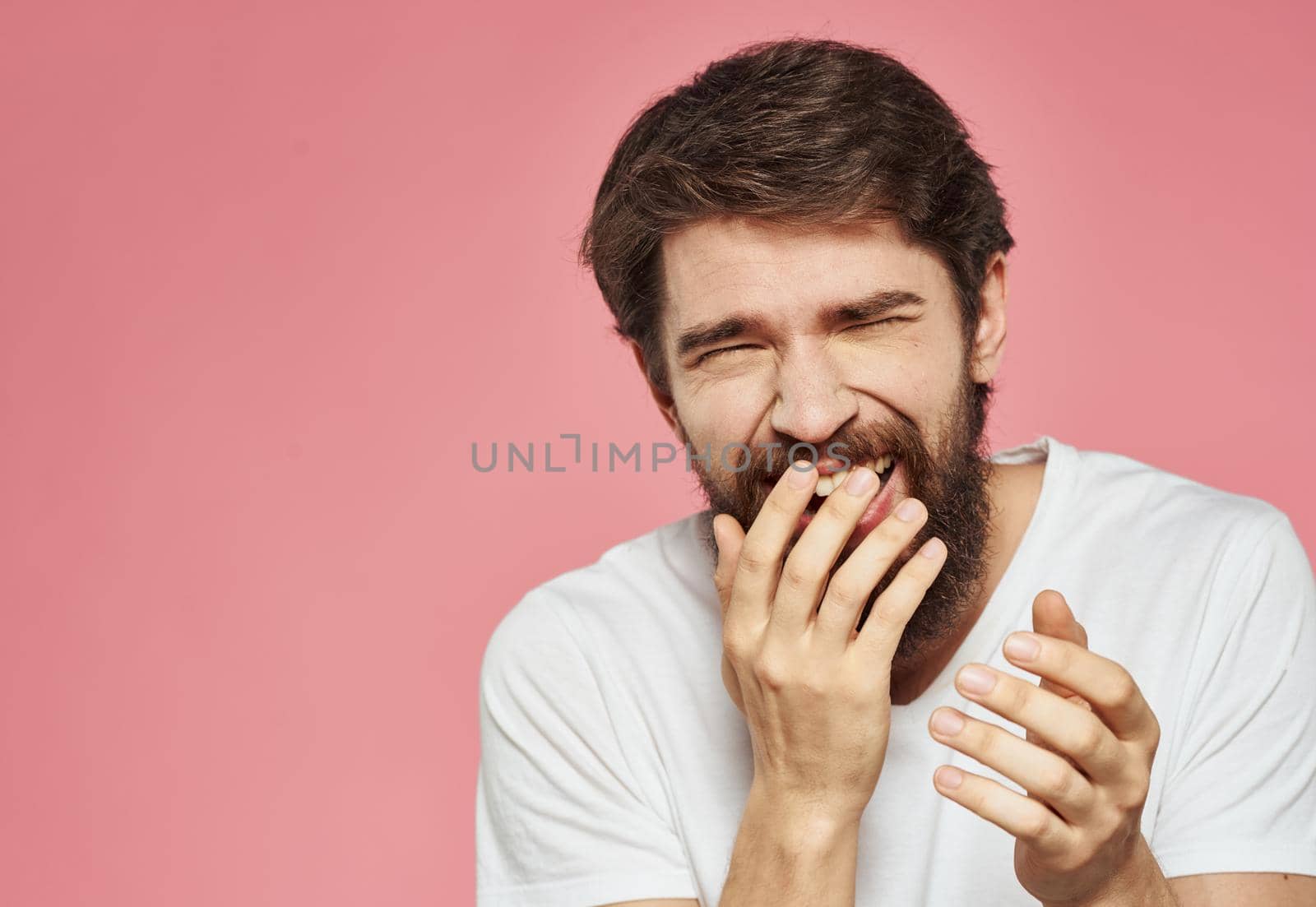 Portrait of a guy in a white t-shirt on a pink background cropped view of fun emotions. High quality photo